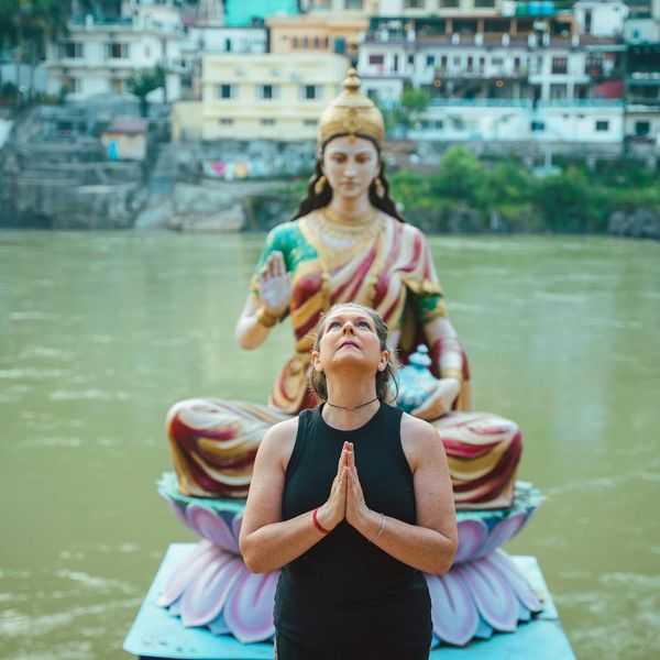 Smiling person meditating outdoors with a serene natural background.